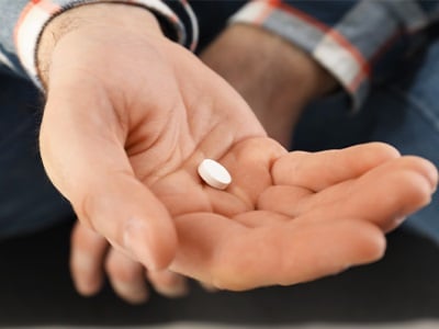 Ein Mann hält eine Pille in der Hand