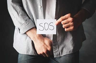 Ein Mann hält ein "SOS"-Schild wegen Prostatitis.