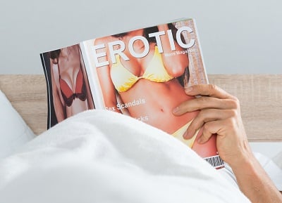 Ein Mann liest ein Pornomagazin, um zu masturbieren.