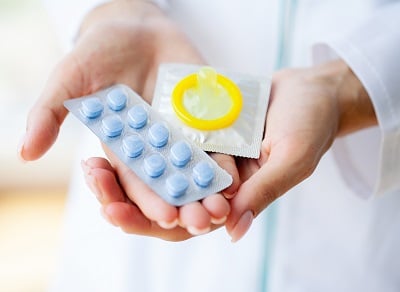 Eine Ärztin mit einer Pille für die Männergesundheit und einem Kondom.