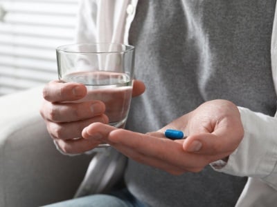 Ein Mann mit einer blauen Pille und einem Glas Wasser