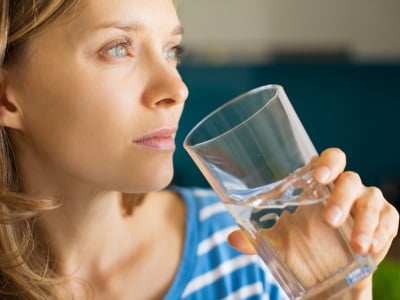  Eine Frau trinkt Wasser aus einem Glas.