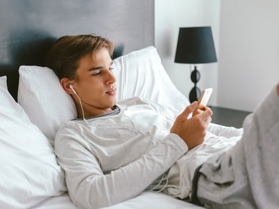Ein Teenager hört Musik und entspannt sich im Bett