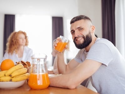 Ein lächelnder, gut aussehender Mann beim gesunden Frühstück