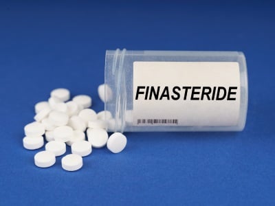 Ein Fläschchen und lose Finasterid-Tabletten