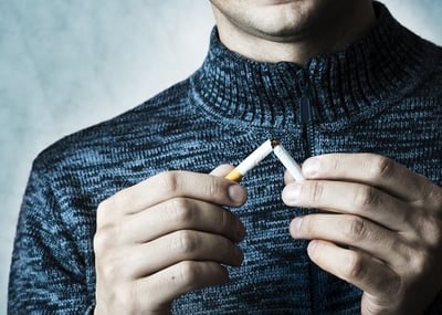 Ein Mann bricht eine Zigarette als Schritt zur sexuellen Gesundheit ab