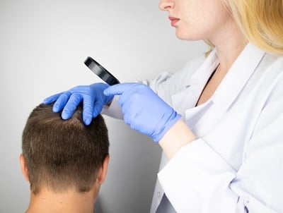 Eine Ärztin bei der Untersuchung der Kopfhaut eines Mannes