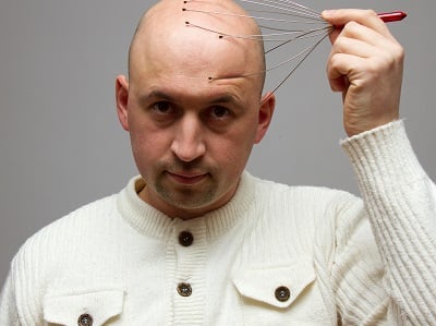 Ein Mann mit Glatze bei der Kopfhautmassage