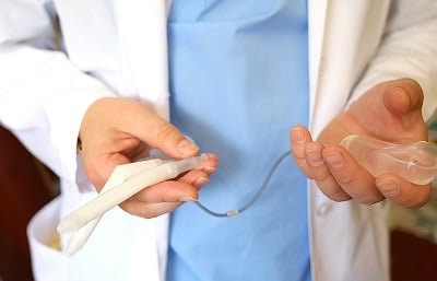  Ein Arzt hält eine Penisprothese in seinen Händen
