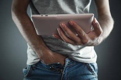 Mann sieht Erwachsenenvideo auf Tablet als Konzept von Porno und Masturbation