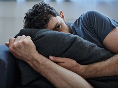 Ein frustrierter Mann liegt mit Depressionen auf dem Sofa