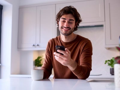 Ein Mann erledigt fröhlich Online-Einkäufe mit seinem Smartphone