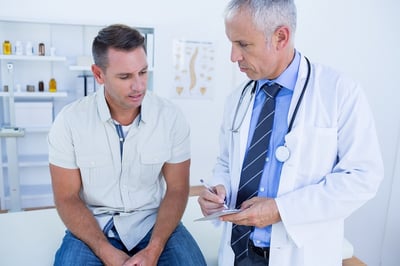 Ein Arzt erklärt einem Mann, welche Medikamente die Spermienqualität verbessern können