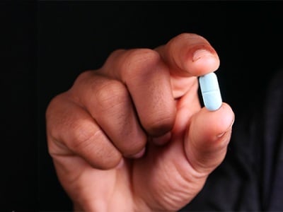 Eine blaue Pille in der Hand eines Mannes