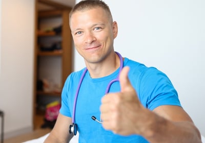 Männlicher Arzt, der mit einer Daumen-hoch-Geste zur Vorsorgeuntersuchung für Männer aufruft