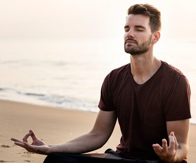 Ein attraktiver Mann praktiziert Yoga am Strand, um sein spirituelles Gleichgewicht zu finden.