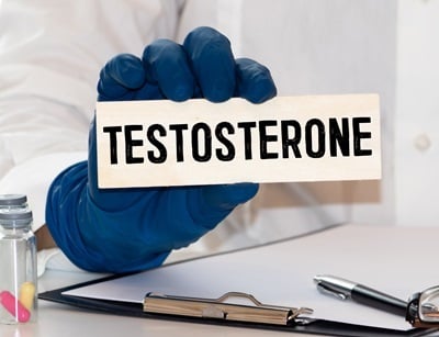 Person mit blauen Handschuhen zeigt ein Schild mit dem Wort Testosteron.