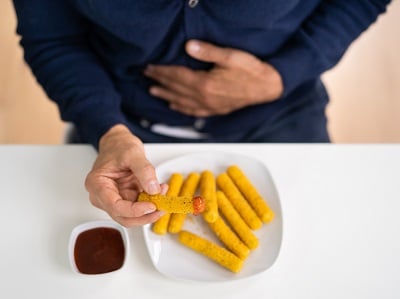 Ein Mann isst Fast Food, das schlechtes Cholesterin enthält