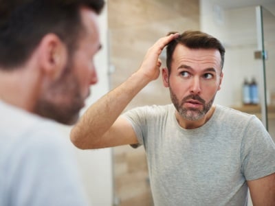 Ein Mann betrachtet seine Haare im Spiegel