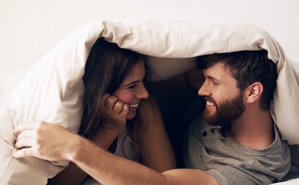 Junges Paar im Bett, das glücklich und zufrieden aussieht